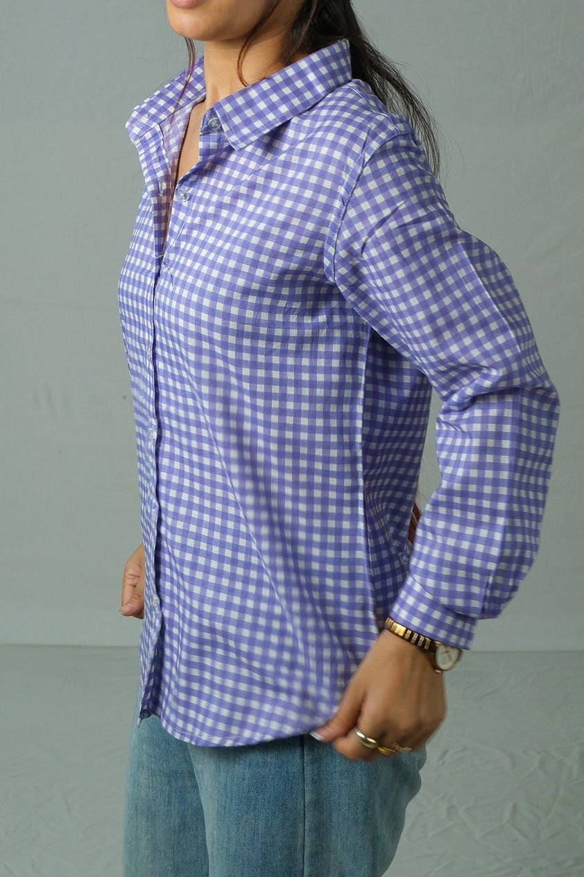 Woman wearing a purple checkered shirt against a plain background